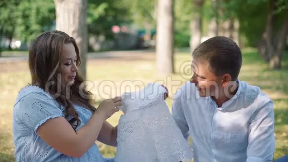 怀孕的夫妇在公园看婴儿装视频的预览图