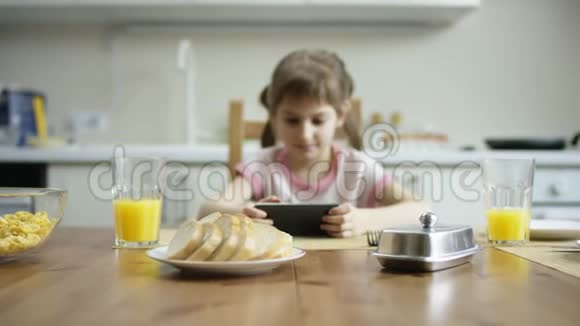高兴的女孩坐在午餐时拿着电话用流动相机在上面玩视频的预览图