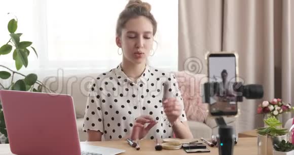 美女vlogger在手机摄像头前展示化妆品视频的预览图