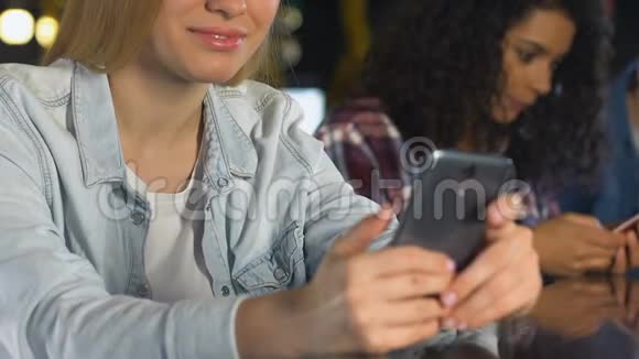 微笑着女人在酒吧的智能手机上聊天使用约会应用程序结识朋友视频的预览图