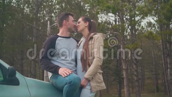 一对年轻夫妇一个男人和一个女孩站在森林里的一辆车上他们亲吻和拥抱视频的预览图