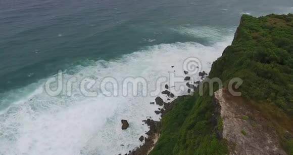 美丽的海洋海浪拍打着巴厘岛海岸的岩石4k视频的预览图