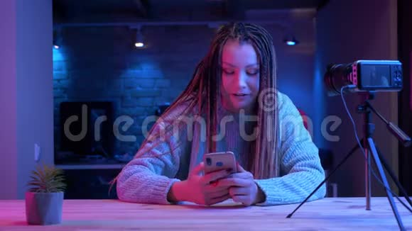 年轻有魅力的女性博客写手特写镜头她带着可怕的表情在手机上笑着欢快地播放现场直播视频的预览图
