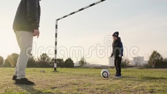 爸爸和儿子在春天的户外玩足球日落时慢动作视频的预览图