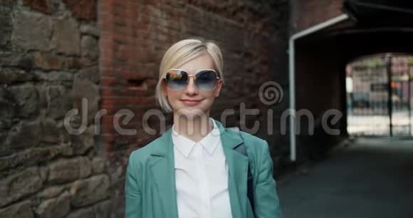 欢快的金发女郎在街上微笑着摘下太阳眼镜视频的预览图