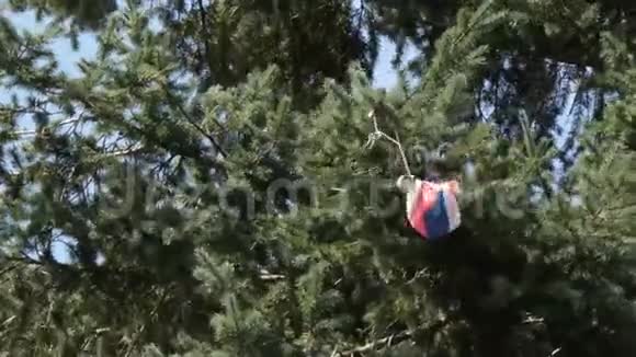 戴着玩具降落伞的人挂在绿树上视频的预览图
