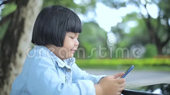 坐在公园里看手机的女孩视频的预览图