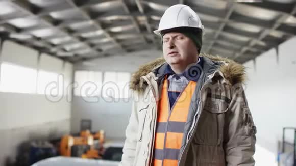一个戴着安全帽穿着工作服的人正站在机库的中间用手机在镜头前发短信视频的预览图