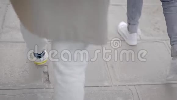 在腿和人行道的框架内两个现代女人穿着运动鞋走在人行道上视频的预览图