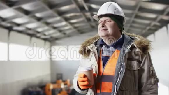 戴着安全帽穿着工作服的人正站在机库的中间在机库里喝杯咖啡休息一下视频的预览图