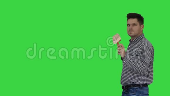 画家步行和用刷子指向他想在绿色屏幕上画的东西Chroma键视频的预览图