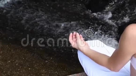 年轻女子在瀑布处练习瑜伽和冥想镜头从左向右缓慢移动视频的预览图
