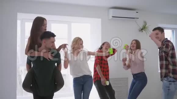 在一个家庭聚会上一群多种族的朋友手里拿着塑料杯在一现代化的大公寓里跳舞视频的预览图