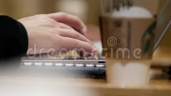 一个年轻人坐在有笔记本电脑的小咖啡馆里的桌子旁视频的预览图