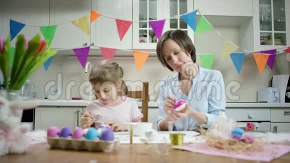 母女俩坐在餐桌旁一起用彩蛋做窝在厨房里干活视频的预览图