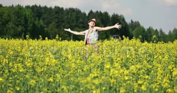 快乐的年轻女子在夏天的油菜田里跳舞视频的预览图