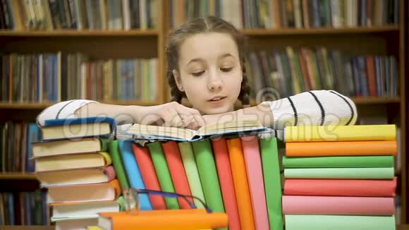快乐的女孩在图书馆看书时大笑视频的预览图