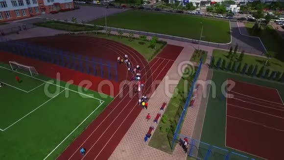 校园鸟瞰图中儿童团体在运动场行走视频的预览图