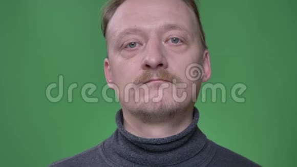 有胡子的中年男子对着镜头观看没有情绪在绿色背景下向右倾斜视频的预览图