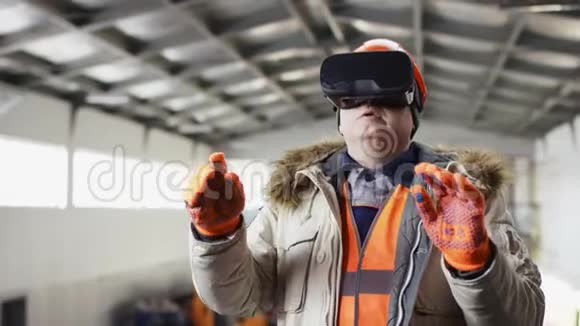 戴着安全帽和工作服的人正站在机库中间用虚拟现实眼镜改变设置视频的预览图