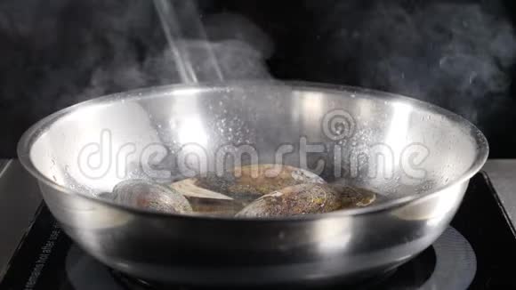 美丽的慢动作美食视频厨师手戴蓝色手套把贝类放在热不粘煎锅上溅出的油视频的预览图