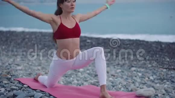 在海边一位运动的女子仰着身体伸展双手做瑜伽姿势视频的预览图