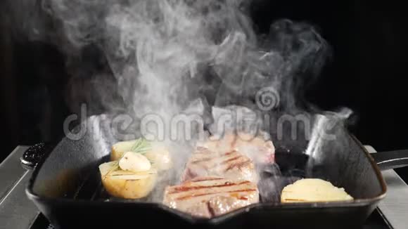 专业厨师在餐厅厨房工作烤架上有土豆和肉白烟笼罩着美味的食物慢镜头视频的预览图
