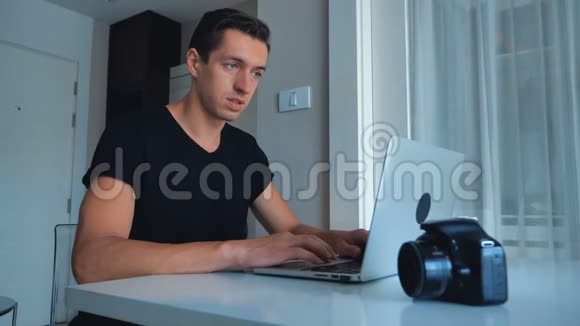年轻的摄影师在家里用笔记本电脑处理图像摄像机外部硬盘躺在旁边视频的预览图