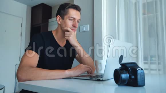 年轻的摄影师在家里用笔记本电脑处理图像摄像机外部硬盘躺在旁边视频的预览图