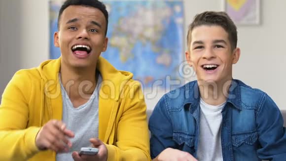 两个青少年在电视上笑看喜剧电影站起来表演情景喜剧视频的预览图
