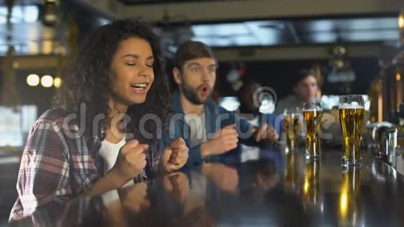 在酒吧里和朋友一起看体育比赛的双种族女孩的快乐时光视频的预览图