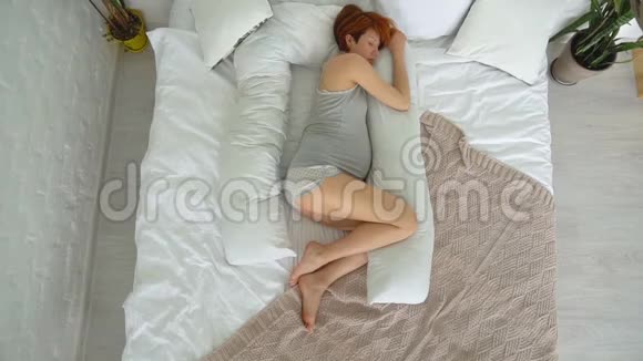 躺在床上躺在枕头上的年轻孕妇视频的预览图