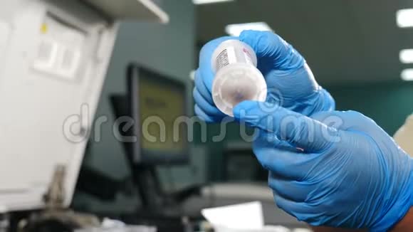 生物医学实验室双手戴蓝色手套手持带有生物材料的医用试管进行分析血液测试视频的预览图
