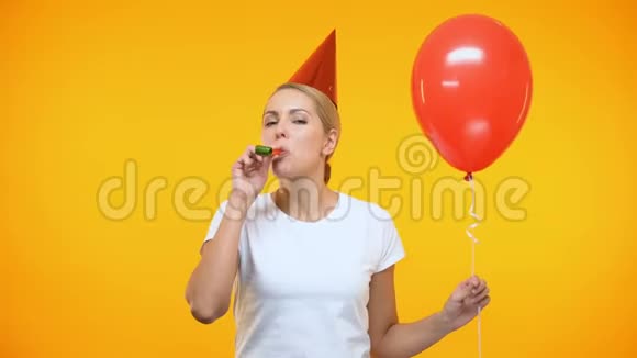 快乐的年轻女士戴着派对帽吹着喇叭拿着红气球过生日视频的预览图
