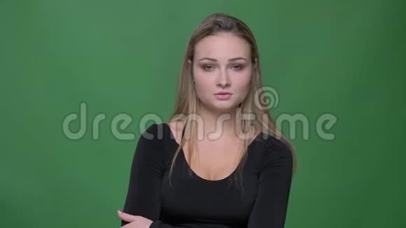 穿着黑色衬衫的年轻女商人在绿色背景下悲伤地看着镜头的肖像视频的预览图