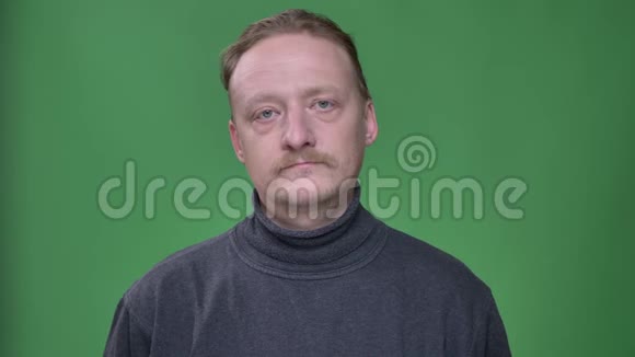 金发中年男子灰色套头衫的肖像悲伤地扭头拒绝或不同意绿色背景视频的预览图