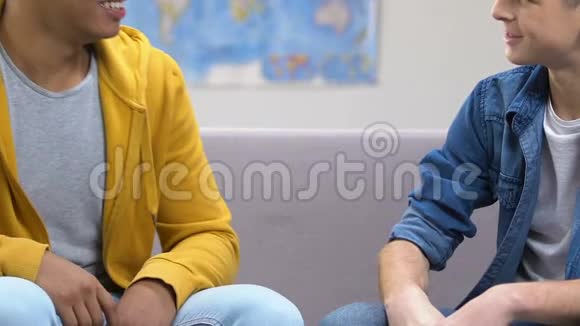 两个十几岁的男朋友打招呼坐在沙发上高中生视频的预览图