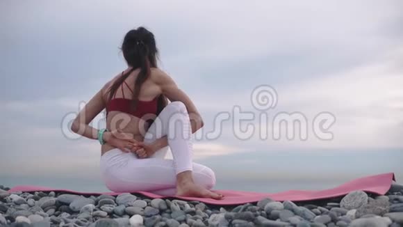 女人正在做身体扭曲坐在海岸瑜伽练习和体操视频的预览图