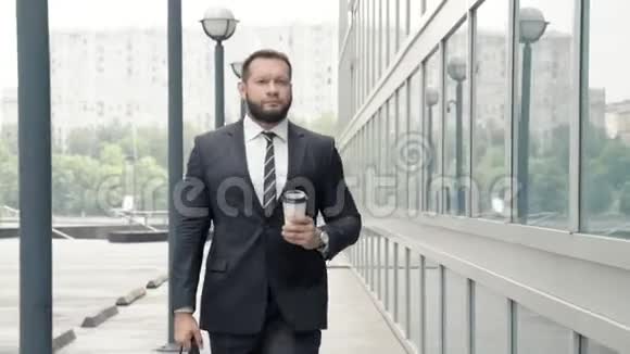 商务男士带着咖啡走在办公楼附近视频的预览图