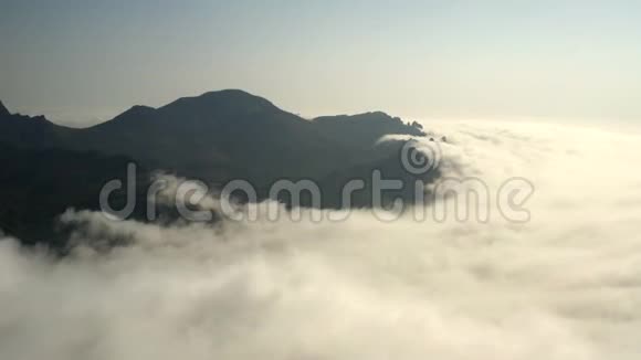 前景中密集的白云山峰上覆盖着巨大的云团视频的预览图