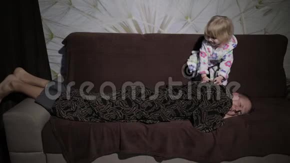穿着浴袍的小女孩叫醒了她的父亲男人睡在沙发上视频的预览图
