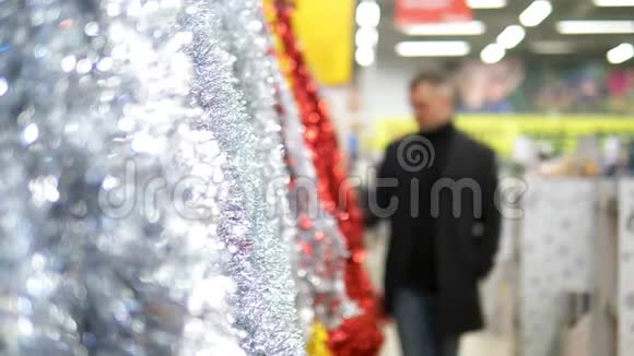 穿外套的年轻人在超市里挑选圣诞装饰品视频的预览图