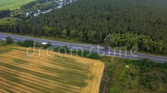 白色卡车在茂密的森林中行驶在高速公路上在森林沥青路上行驶的空中镜头公路视频的预览图
