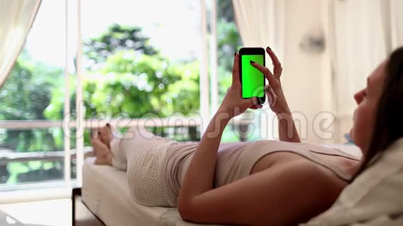 女人躺在床上有智能手机阿尔法频道视频的预览图