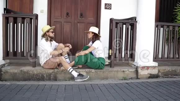 年轻时尚的夫妇戴着草帽坐在门口视频的预览图