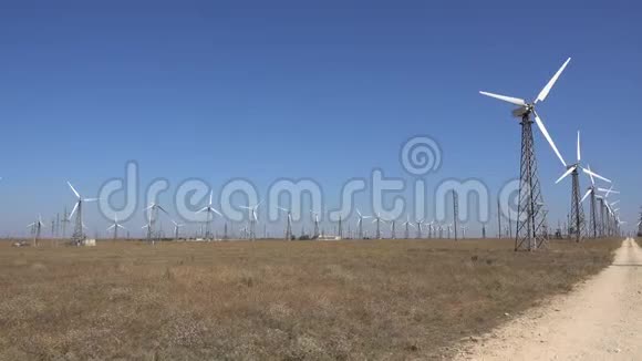 一条乡村公路在一排排高大的风力涡轮机之间视频的预览图