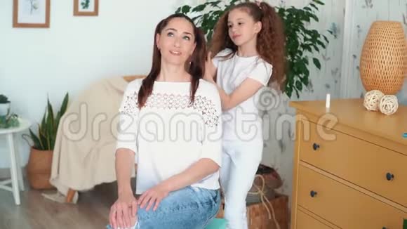 可爱的女孩把她妈妈的头发编成辫子慢动作视频的预览图