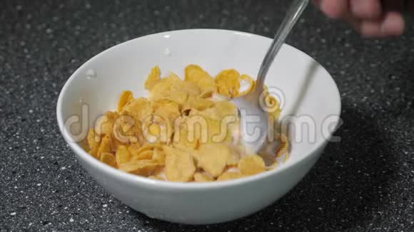 人们正在用勺子把玉米片和牛奶混合在碗里吃早餐视频的预览图