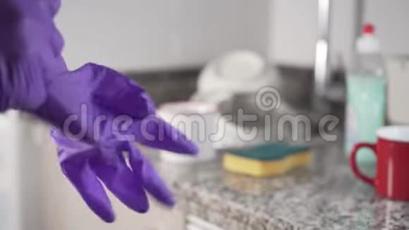 穿衣服的年轻人拉着他的左蓝色保护手套洗碗视频的预览图