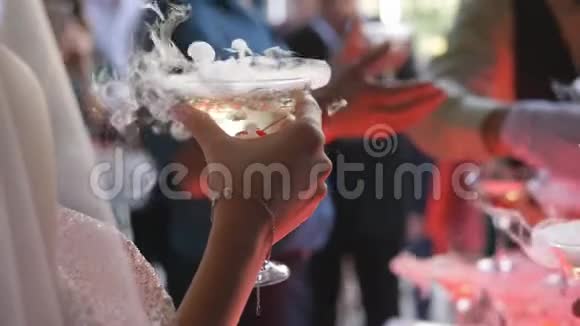 新郎新娘正拿着热气腾腾的香槟酒杯新婚夫妇手里拿着香槟在玻璃杯里放干冰视频的预览图